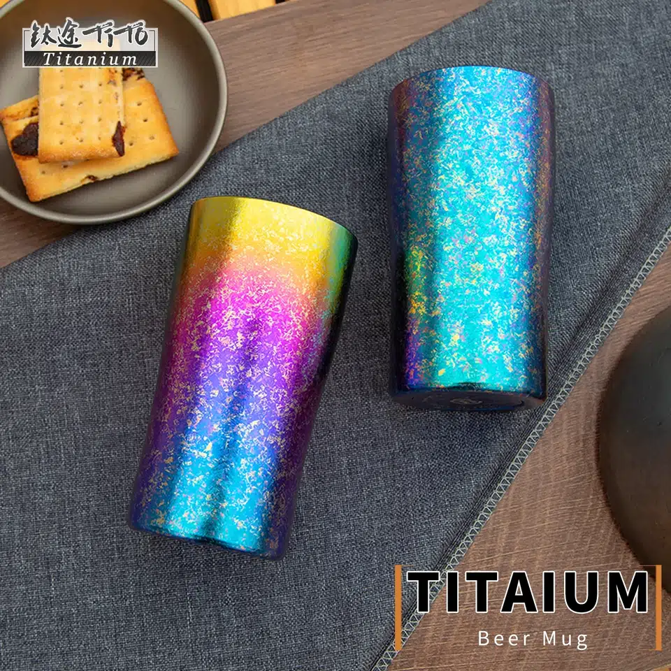 Two sample mugs on a gray linen texture fabric with a walnut table underneath, a small titanium plate with two cookies in the top left corner.